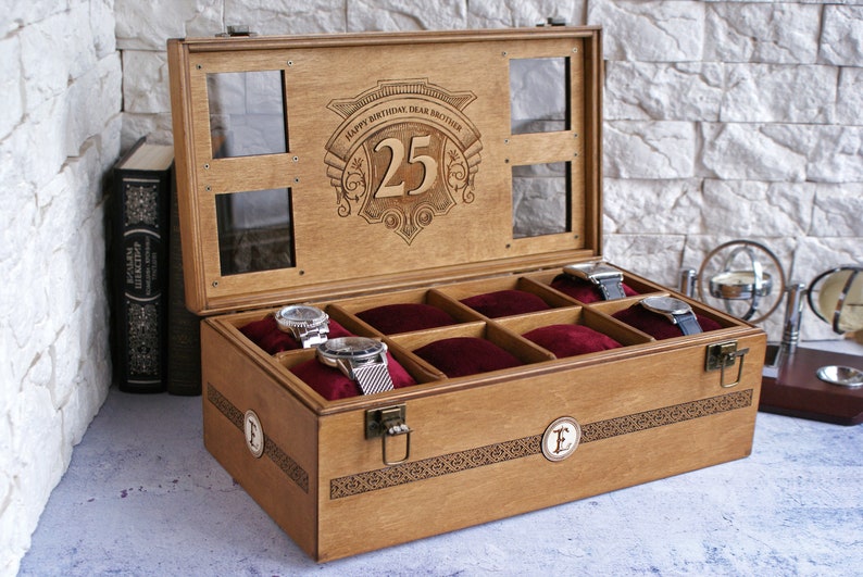 May include: A wooden watch box with a glass top and eight compartments lined with red velvet. The lid is engraved with the text "Happy Birthday Dear Brother 25".