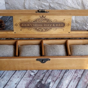 May include: A wooden box with a hinged lid and a clear glass window. The lid is engraved with the text "вижу цель, иду к ней" and a crown. The box has four compartments lined with fabric.