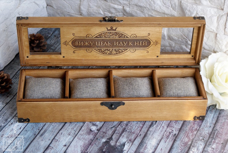 May include: A wooden box with a hinged lid and a clear glass window. The lid is engraved with the text "вижу цель, иду к ней" and a crown. The box has four compartments lined with fabric.
