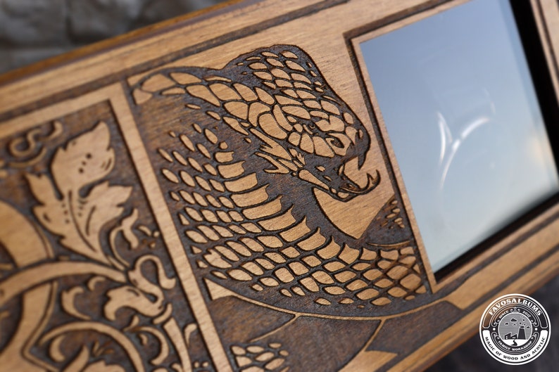 May include: A wooden box with a laser-engraved design of a snake on the front. The box has a small glass window on the right side. The box is labeled "Favosal Bums" with the text "Hall of Wood and Activity".