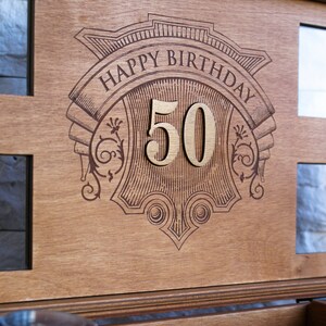 Puede incluir: Una caja de madera con un dise&ntilde;o grabado decorativo que dice "Happy Birthday 50".
