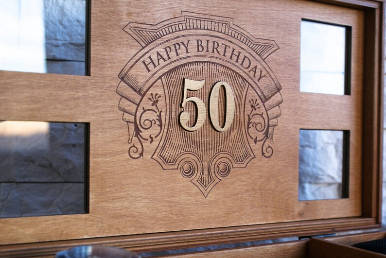 Puede incluir: Una caja de madera con un dise&ntilde;o grabado decorativo que dice "Happy Birthday 50".