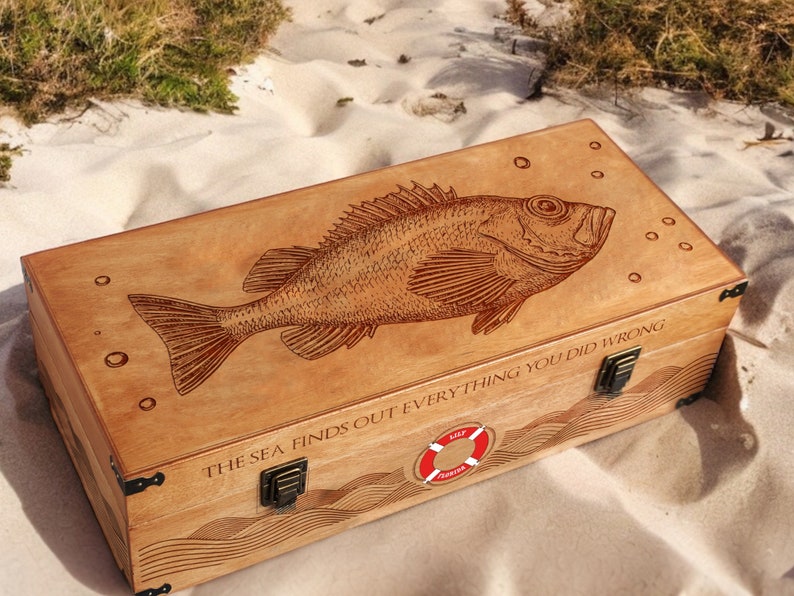May include: A wooden box with a carved fish design and the text "The sea finds out everything you did wrong". The box has a red life preserver logo and metal clasps.