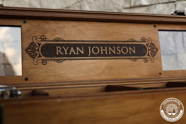 May include: A wooden box with a personalized inscription that reads "RYAN JOHNSON" in a decorative font. The box has a dark brown stain and a clear glass window on each side.