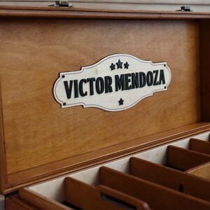 May include: A wooden box with a hinged lid and a personalized sign that reads "Victor Mendoza". The box has multiple compartments inside.