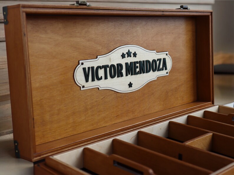 May include: A wooden box with a hinged lid and a personalized sign that reads "Victor Mendoza". The box has multiple compartments inside.
