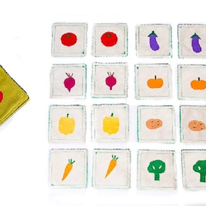 May include: A set of 16 felt squares with different vegetable images, including tomatoes, eggplants, beets, pumpkins, peppers, potatoes, carrots, and broccoli. The squares are white with green stitching around the edges.