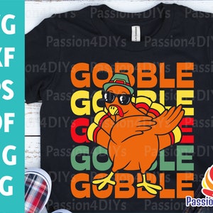 May include: A black t-shirt with a retro-style design featuring a cartoon turkey wearing sunglasses and a hat. The text "GOBBLE" is repeated in a colorful, layered design.