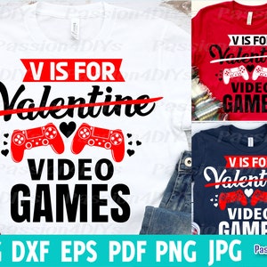 以下が含まれることがあります： ビデオゲームコントローラーのグラフィックと「V is for Valentine Video Games」というテキストが書かれた白、赤、青のTシャツデザインです。