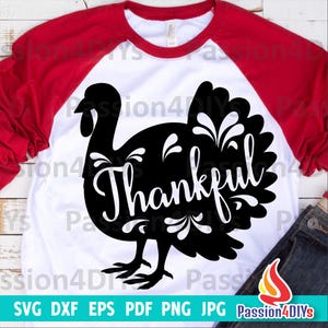 May include: A white t-shirt with a red raglan sleeve design. A black silhouette of a turkey with the word "Thankful" inside the turkey's body. The turkey has a floral design on its feathers.
