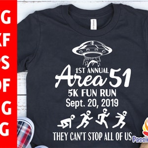 May include: Black t-shirt with white graphic text and illustrations. The design includes a UFO, the words "1st Annual Area 51 5K Fun Run Sept. 20, 2019," and alien figures running. The phrase "THEY CAN'T STOP ALL OF US" is also included.