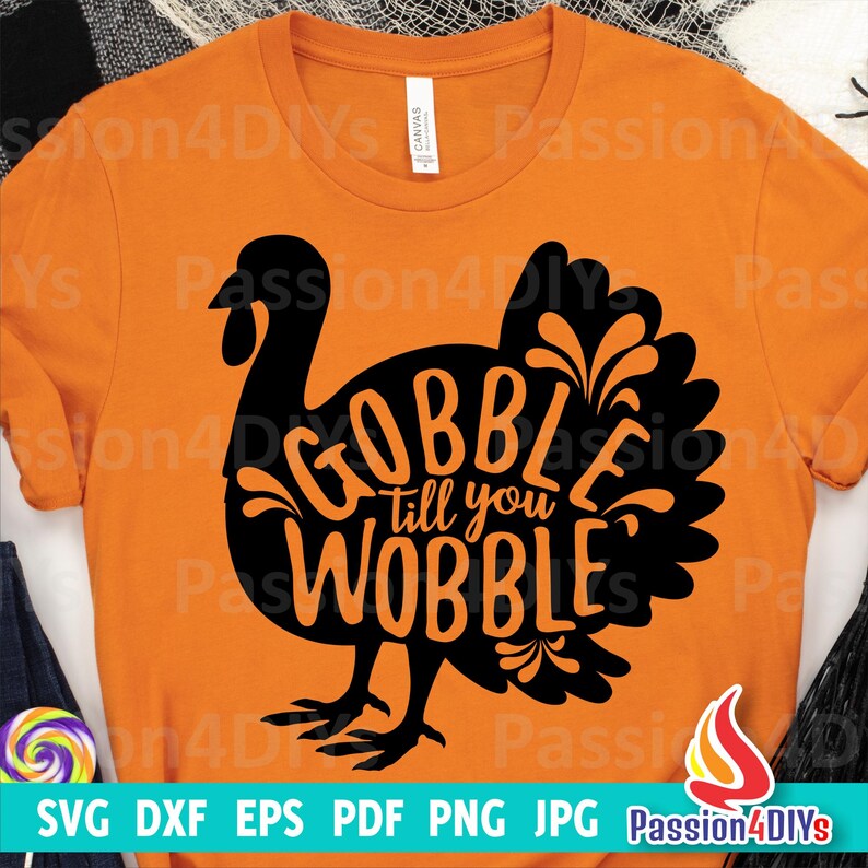 May include: A black and orange graphic design of a turkey with the text "Gobble till you wobble" inside the turkey silhouette. The design is on a bright orange t-shirt.