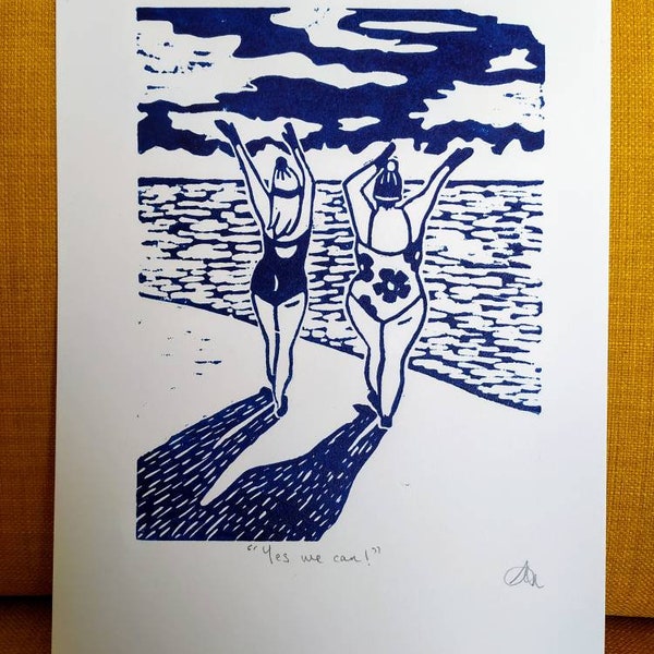 Original lino print featuring cold water sea swimmers on Worthing beach. Yes we can!