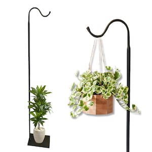 May include: Black metal plant stand with a curved hook, holding a hanging wooden planter with a green and white plant. A potted green plant sits on a black base. The stand is designed for outdoor or indoor use.