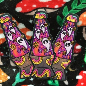 May include: Three colorful lava lamp stickers with a psychedelic design. Each sticker features a lava lamp with a swirling, abstract pattern and a pink, purple, and orange color scheme. The lava lamps are filled with white ghosts and yellow flowers.