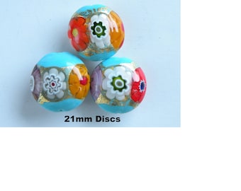 May include: Three round, decorative glass beads with floral designs. The beads are 21mm in diameter and feature a light blue base with colorful flower patterns in red, orange, white, and purple. Gold accents are also present.