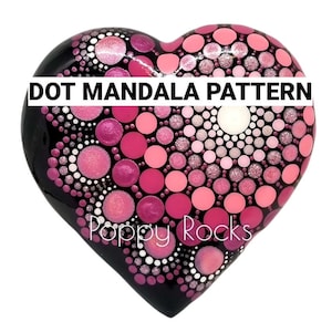 May include: A heart-shaped rock painted with a pink and white dot mandala pattern. The rock is black and has the words "DOT MANDALA PATTERN" and "Poppy Rocks" written on it.