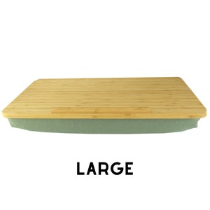 Puede incluir: Una bandeja grande para portátil de bambú rectangular con un cojín de tela verde. La bandeja tiene un soporte para teléfono integrado y está etiquetada como "LARGE".