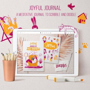 May include: A digital tablet displaying a mockup of a journal cover with the text "Joyful Journey to Self Discovery" and "Joynal" in pink and yellow. The journal cover features a cartoon illustration of a person sitting in a chair with a cat and a plant. The tablet is on a wooden surface with a yellow marker and a cup of coloured pencils.