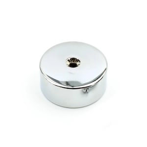 May include: A cylindrical metal knob with a polished chrome finish. The top surface is smooth and flat with a centred circular hole. A small metal screw is visible protruding from the side of the base, indicating a mounting mechanism.