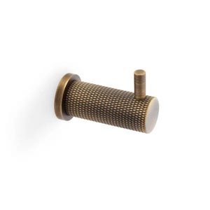 May include: A cylindrical wall hook with a dark brass finish and a textured, diamond-patterned surface. The hook features a circular base plate and a small, vertical peg extending from the top of the main body for hanging items securely.