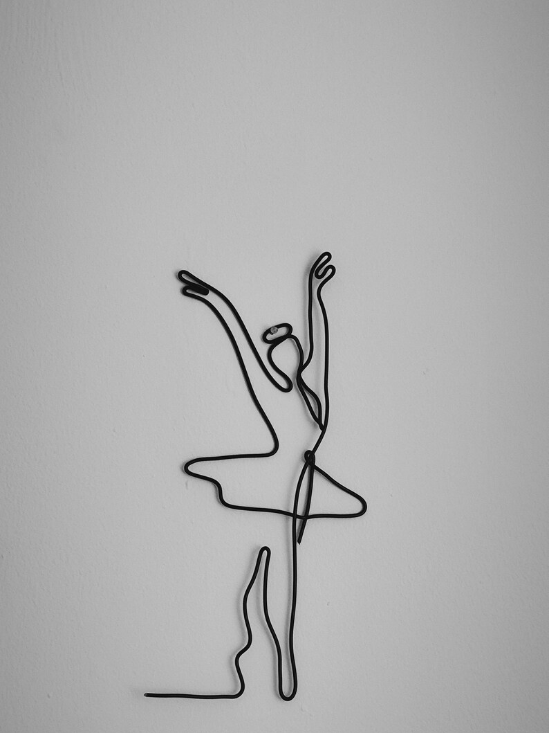 May include: A black wire sculpture of a ballerina in a pose with arms raised above her head.