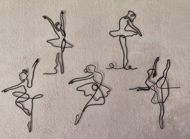 May include: Five black wire sculptures of ballerinas in various poses. The sculptures are made of thin wire and are delicate in appearance.