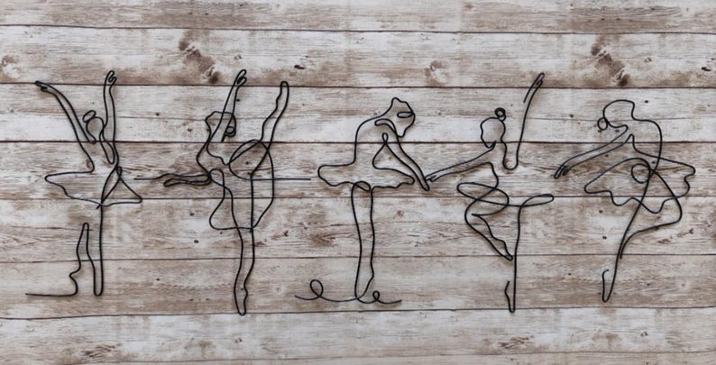 May include: Five black wire sculptures of ballerinas in various poses on a wood background.