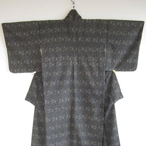 Puede incluir: Un kimono negro con un patrón geométrico. El kimono está colgado en una percha.