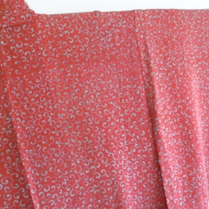 Puede incluir: Un kimono rojo con un patrón de espiral blanco. La tela es suave y sedosa.