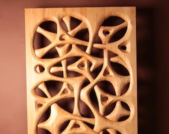 Könnte beinhalten: Ein Wandkunststück aus Holz mit einem geschnitzten Design aus komplizierten, sich überlappenden Kreisen und Kurven. Das Stück ist aus hellbraunem Holz gefertigt und hat eine natürliche Oberfläche.