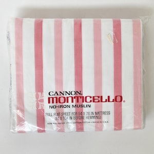 May include: A Cannon Monticello no-iron muslin full flat sheet in a white and pink vertical striped pattern, packaged in clear plastic. The label specifies it is for a 54 x 76 inch mattress, measuring 81 x 104 inches before hemming, 50% polyester, 50% cotton.