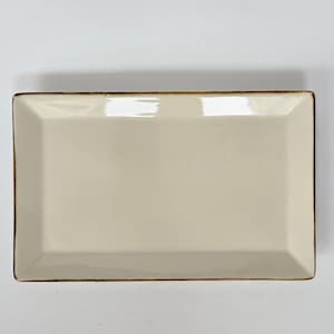 May include: A rectangular, off-white ceramic serving platter with a slightly raised edge and a dark brown trim. The dish has a glossy finish and a simple, elegant design, suitable for serving appetizers or small dishes.