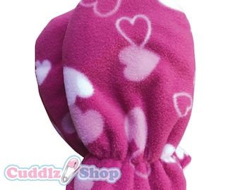 May include: Pink fleece mittens with a white heart pattern. The mittens have a gathered elastic cuff.