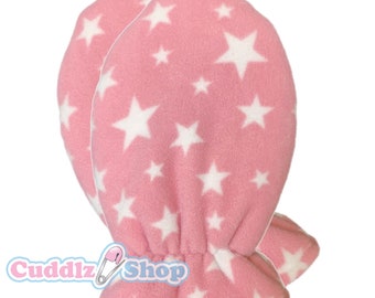 May include: A pair of pink baby mittens with a white star pattern. The mittens have a ruffled edge and are made of soft fleece.