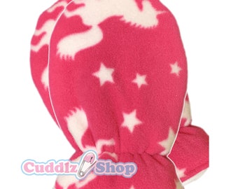 May include: Pink fleece mittens with white unicorn and star patterns. The mittens have a soft texture and a comfortable fit, perfect for keeping hands warm. The Cuddlz Shop logo is visible at the bottom.