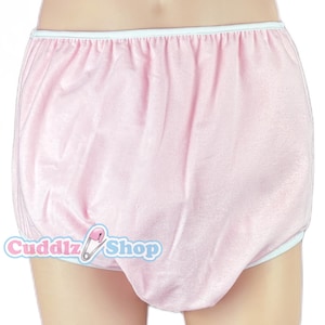 Pode incluir: Fralda para adultos de cor rosa com uma cintura elástica branca. A fralda é feita de um material macio e absorvente. O texto "CuddLz Shop" é impresso na parte frontal da fralda.