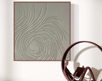 May include: A framed abstract art print with a gray background and a pattern of small circles arranged in a swirling design. The print is hanging on a white wall next to a metal sculpture of a person sitting in a circle.
