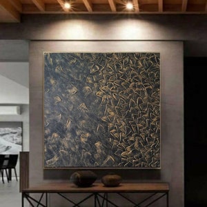 Puede incluir: Pintura abstracta con un diseño texturizado y en capas. La pintura presenta un fondo negro con acentos dorados. Los acentos dorados tienen la forma de pequeños triángulos superpuestos.