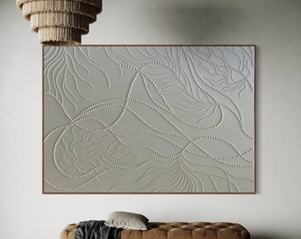 Könnte beinhalten: Ein weißes Wandbild mit einem erhabenen, strukturierten Design aus wirbelnden Linien und Punkten. Die Kunst ist in einem dünnen, braunen Rahmen gerahmt und hängt über einer braunen Bank.
