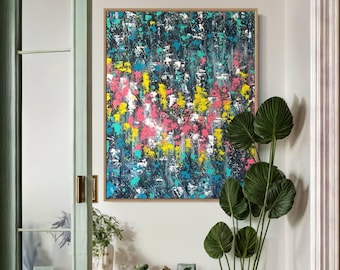 May include: Abstract painting with a colorful, splatter-like design in shades of blue, green, pink, and yellow. The painting is framed and hanging on a white wall.