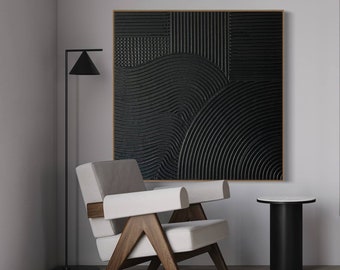 May include: A black and white abstract art print with geometric patterns and lines. The print is framed and hanging on a white wall. A white armchair with wooden legs and a black side table are in the foreground.