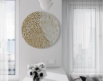 May include: A round wall decor with a textured design. One half of the circle is white with wavy lines, and the other half is gold with a textured dot pattern.