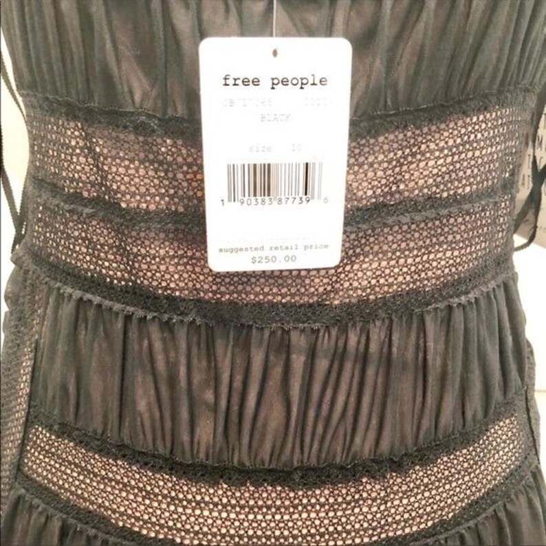 May include: Close-up of a black dress with a layered design. The dress features a lace and sheer fabric construction. A white tag from "free people" is attached, with the size and color information.