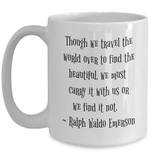 May include: White ceramic coffee mug with a black quote by Ralph Waldo Emerson: "Though we travel the world over to find the beautiful, we must carry it with us or we find it not."