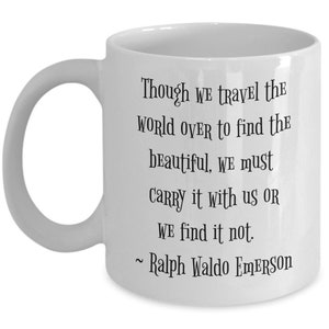 May include: White ceramic coffee mug with a black quote by Ralph Waldo Emerson: "Though we travel the world over to find the beautiful, we must carry it with us or we find it not."