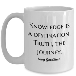 May include: White ceramic coffee mug with a black quote that reads "Knowledge is a destination. Truth, the journey. Terry Goodkind".