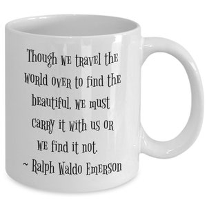 May include: White ceramic coffee mug with a black quote by Ralph Waldo Emerson: "Though we travel the world over to find the beautiful, we must carry it with us or we find it not."