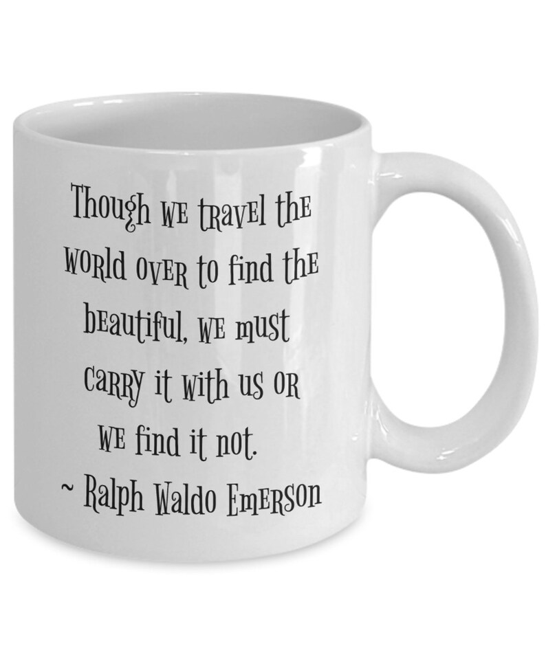 May include: White ceramic coffee mug with a black quote by Ralph Waldo Emerson: "Though we travel the world over to find the beautiful, we must carry it with us or we find it not."