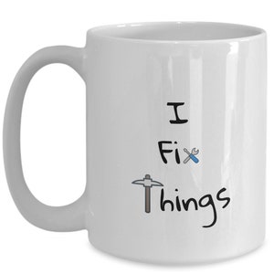 May include: White ceramic coffee mug with black text that reads "I Fix Things" and a black and grey pickaxe and a blue and grey screwdriver.